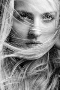 Nahaufnahme eines Gesichts mit wehenden Haaren, intensiver Blick im Schwarz-Weiß-Portrait, aufgenommen im Fotostudio Hamburg.